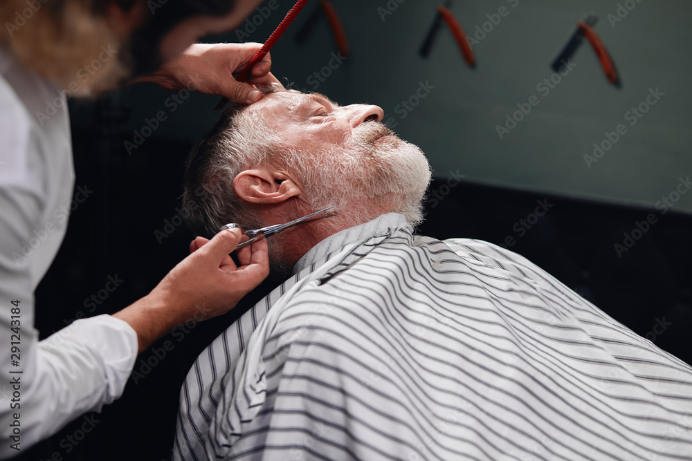 man cutting his client's beard with scissors.close up portrait, man cutting his client's beard with scissors.close up portrait,
