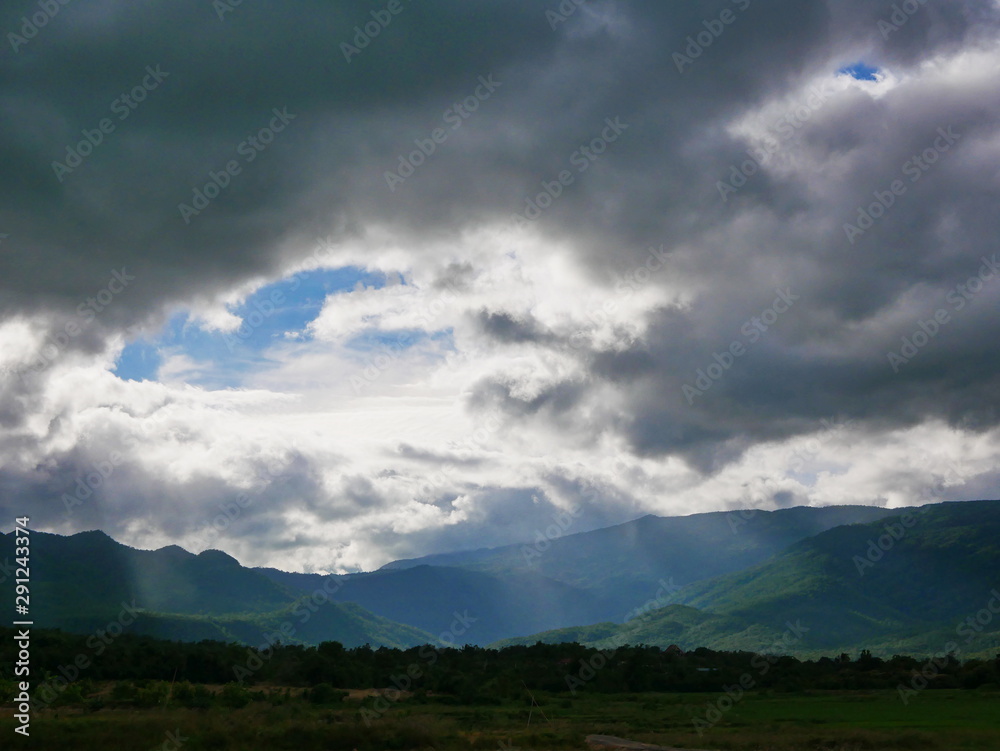 Beams of sunlight shining through dark rainy clouds  after rain down on the earth