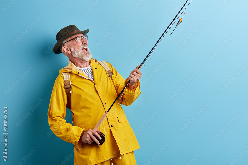 excited senior man expressing positive feeling and emotion while catching fish. close up photo. isolated blue background excited senior man expressing positive feeling and emotion while catching fish. close up photo. isolated blue background
