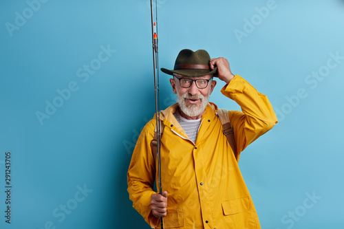 cheerful old man has noticed a big fish in the lake, man staring at gold fish. close up photo. isolated blue background, copy space
