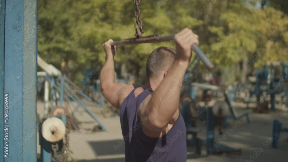 Determined muscular bodybuilder doing lat pulldown heavy weight exercise for back with bar