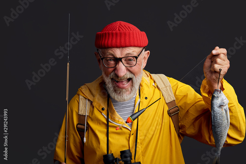 funny positive man rejoicing at fish which he has cought in the lake, success and happiness concept. close up photo. isolated black background photo