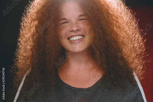 Portrait of ethnic redhead curly-haired woman with freckles.