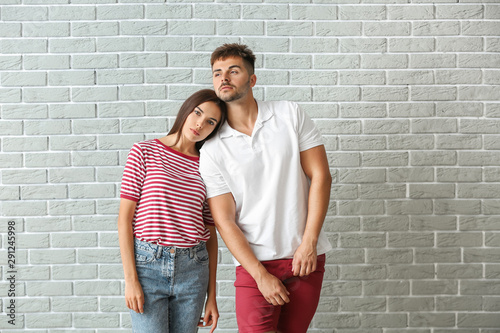 Fashionable young couple against brick wall