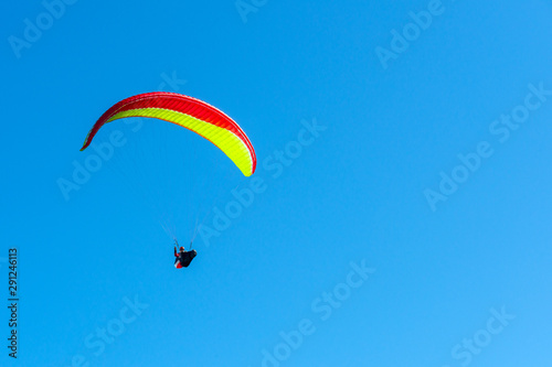 Gelb-roter Paraglider vor blauem Himmel