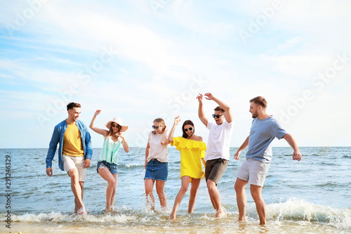 Happy friends having fun on sea beach at resort