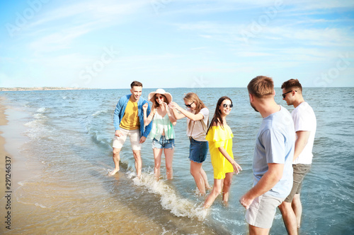 Happy friends having fun on sea beach at resort