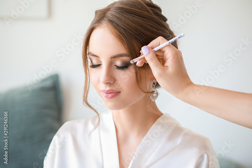Foto Professional makeup artist working with young bride at home