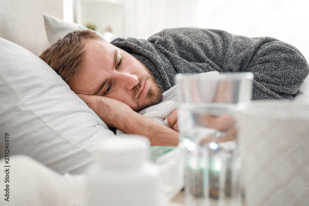Man ill with flu lying in bed - obrazy, fototapety, plakaty 