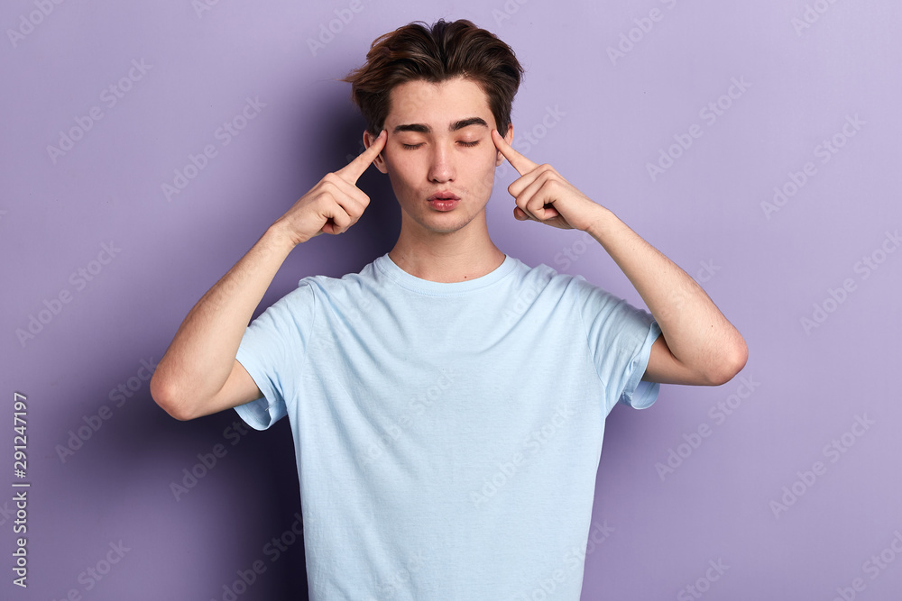 young relaxed man holds fingers on temples, has bad memory, tries to concentrate and remember details of accident. meditation, free time, health care, lifestyle , isolated blue background, studio shot young relaxed man holds fingers on temples, has bad memory, tries to concentrate and remember details of accident. meditation, free time, health care, lifestyle , isolated blue background, studio shot
