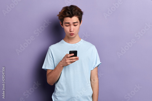 Closeup portrait of handsome young man in casual clothes with , shocked surprised expression looking at the camera , isolated on blue background. Negative human emotions, facial expressions, feeling