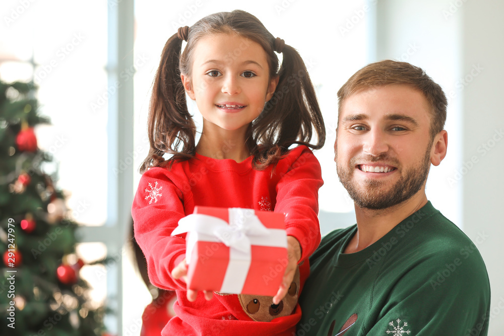Happy father and his little daughter with gift at home on Christmas eve Happy father and his little daughter with gift at home on Christmas eve
