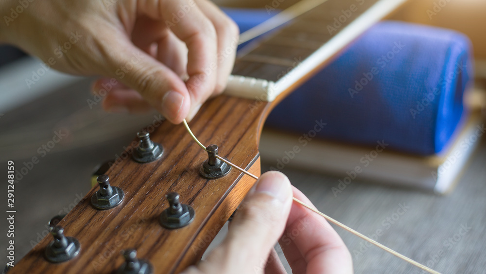 Checking the acoustic guitar string, Expert is tuning the guitar string, Closeup Photos Adobe