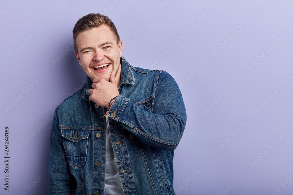 good looking man laughing, having fun in the studion while posing to the camera, close up portrait, isolated blue background. copy space