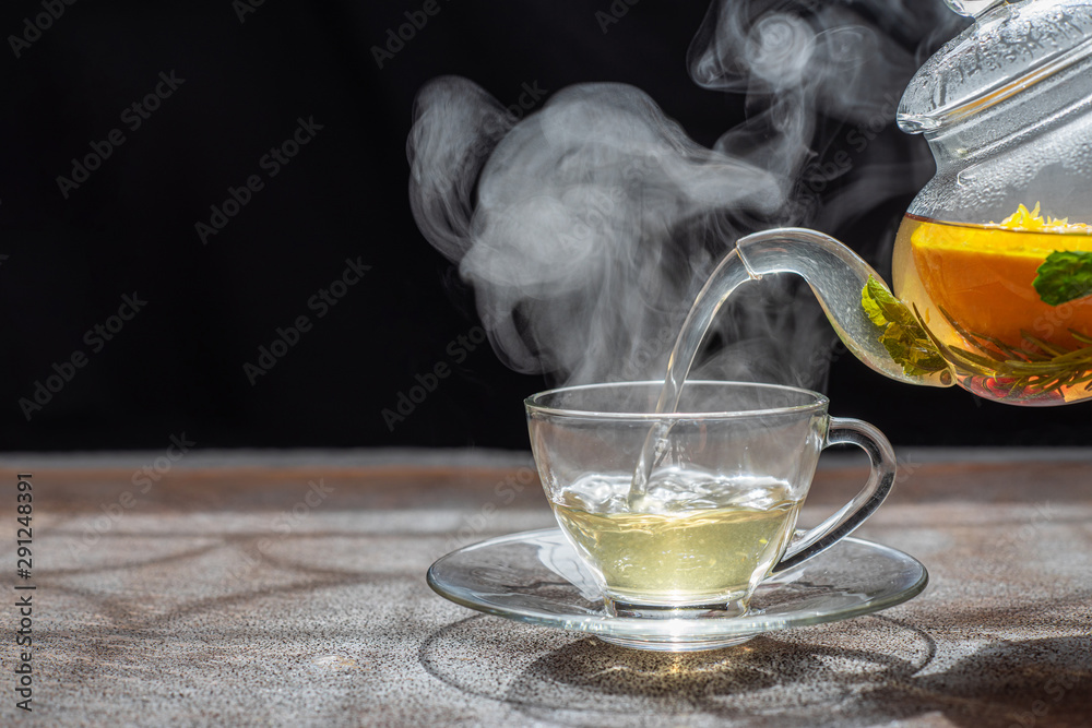 Process brewing tea,dark mood.The steam from hot tea is poured from the kettle into a kettle with tea leaves redcurrant mandarin orange lemon,rosemary, mint.,hot food and healthy meal concept - obrazy, fototapety, plakaty 