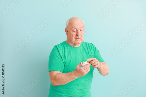 Diabetic man with digital glucometer on light background