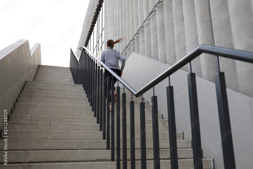 Rear view of runner athlete running on stairs. Woman fitness is jogging oudoors Rear view of runner athlete running on stairs. Woman fitness is jogging oudoors