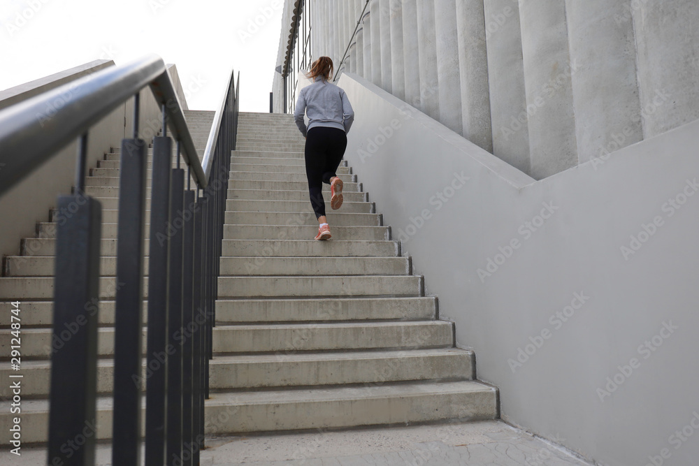 Rear view of runner athlete running on stairs. Woman fitness is jogging oudoors