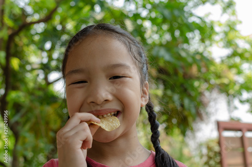Little girl happy and eating potato ship with nature background