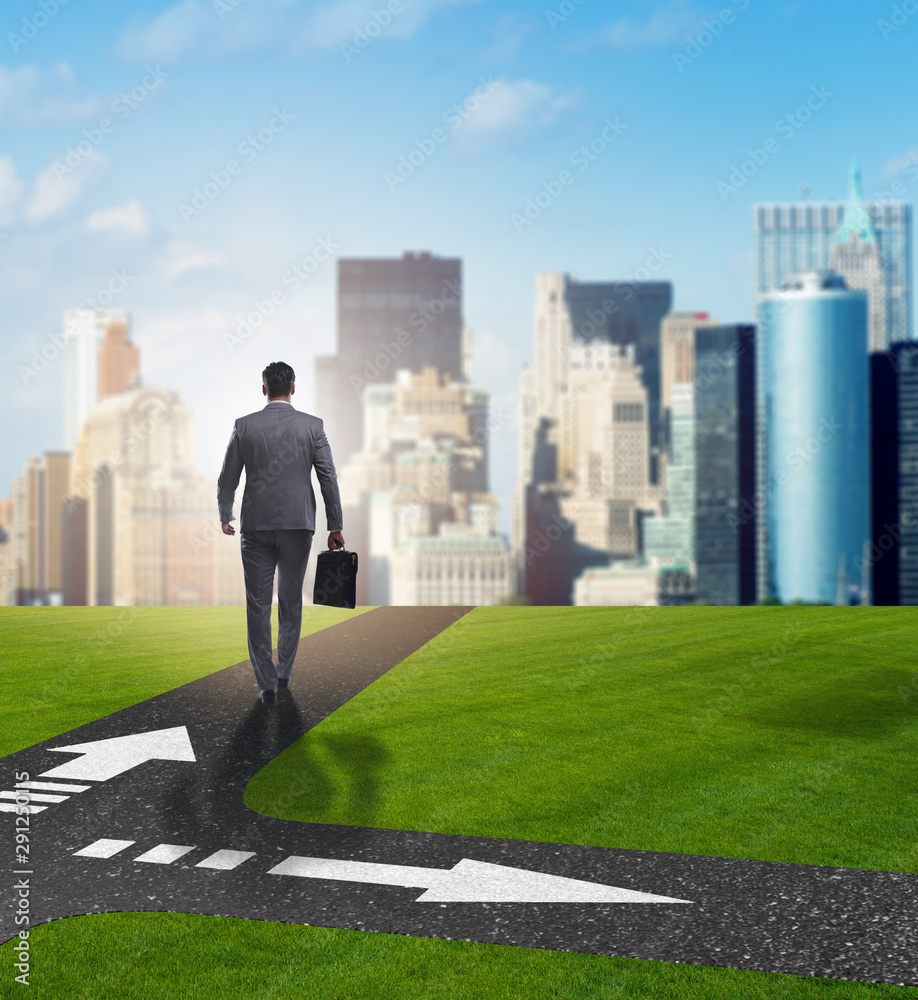 Young businessman at crossroads in uncertainty concept Young businessman at crossroads in uncertainty concept