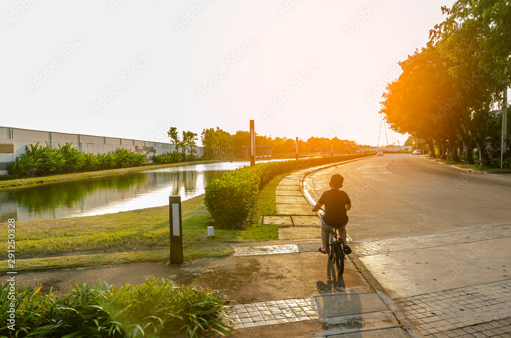 Child riding bycycle with sunset