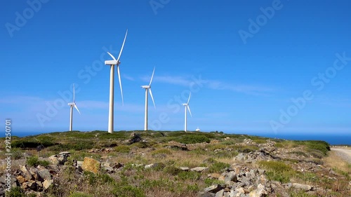 Modern windmills on the island of Crete near Elounda, against a background of blue sky and sea.