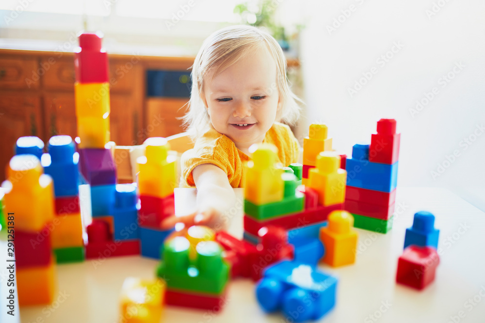 Little girl playing with colorful plastic construction blocks