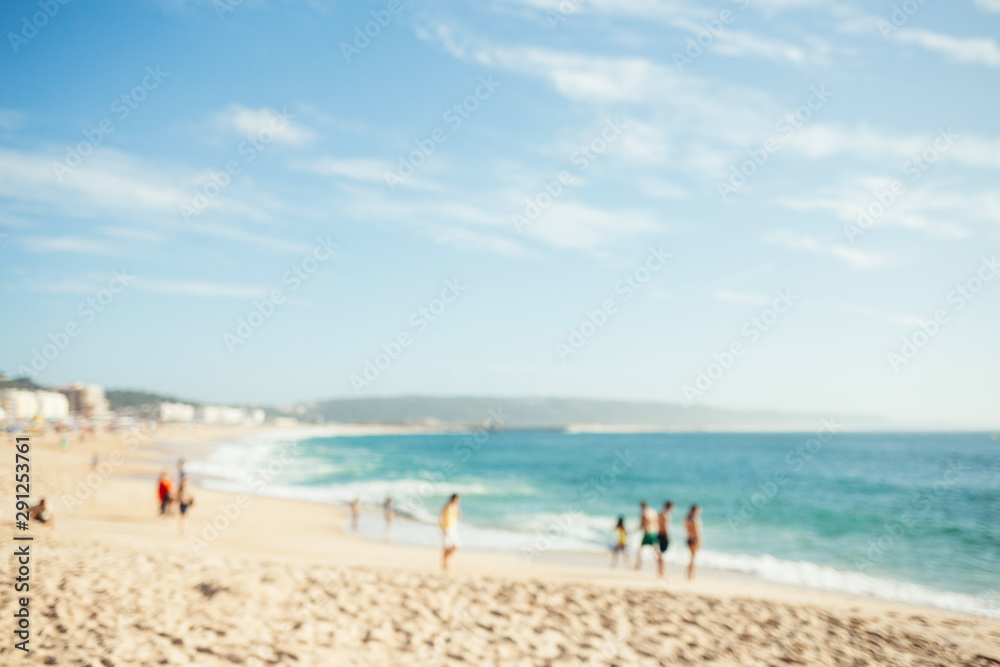 Blurred beach with people and ocean waves. Summer background.