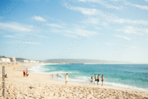 Blurred beach with people and ocean waves. Summer background.