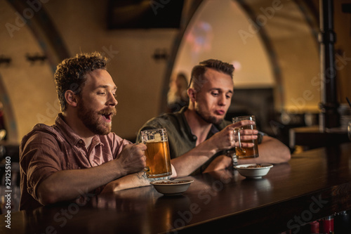 Cheerful friends drinking draft beer in a pub