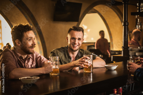 Cheerful friends drinking draft beer in a pub