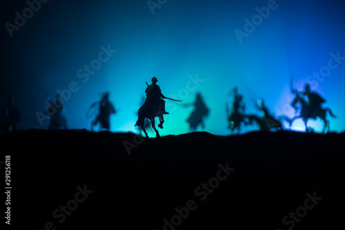 Medieval battle scene with cavalry and infantry. Silhouettes of figures as separate objects, fight between warriors on dark toned foggy background. Night scene. © zef art