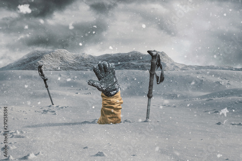 Konstfotografi Hiker stretching out his snow covered hand next to trekking poles to signal help because of snow avalanche