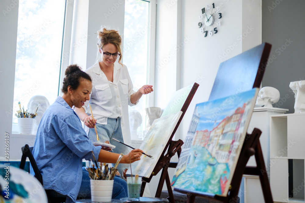 Obraz premium Creative painter and her protege working in a studio
