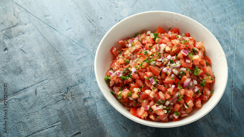 Mexican Tomato Salsa in white bowl with lime, red onion, jalapeno pepper, parsley and tortilla chips