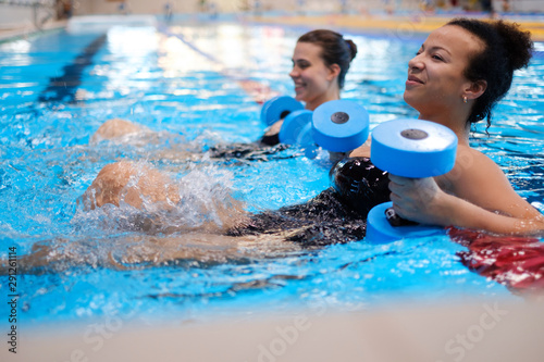 Fototapeta Multiracial couple attending water aerobics class in a swimming pool