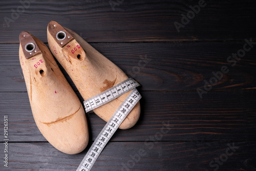 Leather samples for shoes and wooden shoe last on dark wooden table. photo