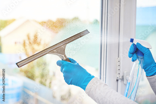 Girl washes the window overlooking the house, sprinkles detergent with foam on the window.