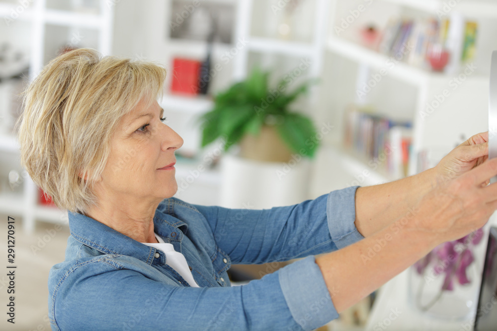 senior woman hanging a picture on the wall senior woman hanging a picture on the wall