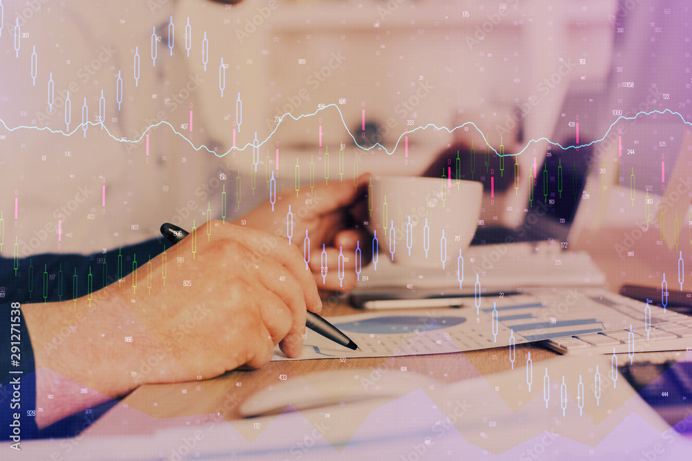 Double exposure of man's hands writing notes of stock market with forex graph.