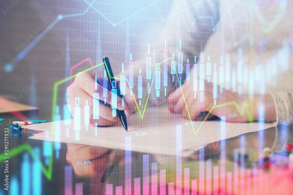 Hand taking notes in notepad. Forex chart holograms in front. Concept of research. Multi exposure Hand taking notes in notepad. Forex chart holograms in front. Concept of research. Multi exposure