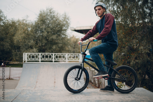 Professional young male sportsman cyclist with bmx bike at skatepark