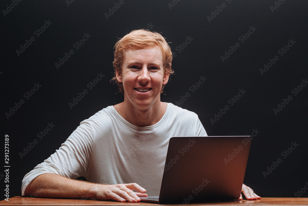 programmer in a white t-shirt on a black background with a laptop programmer in a white t-shirt on a black background with a laptop