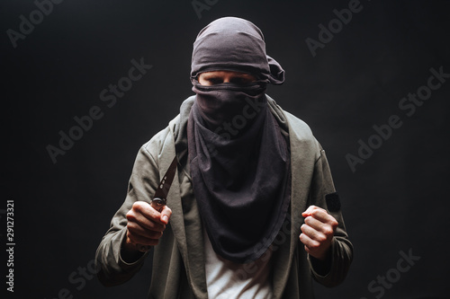  criminal in a mask threatens with a knife the dark background