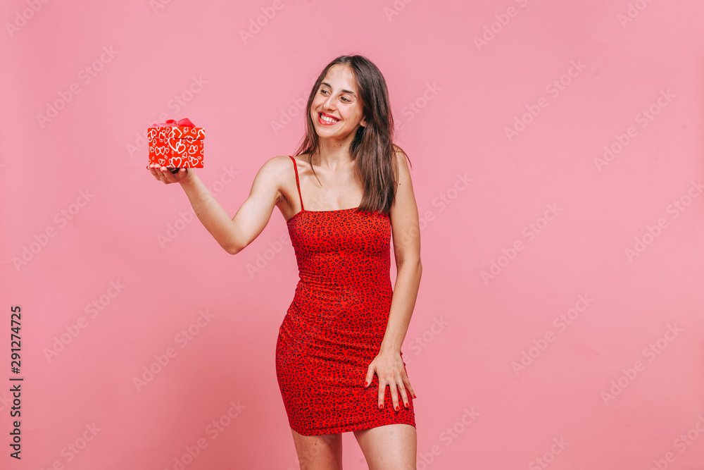 The girl received a box with a gift and rejoices on a pink background The girl received a box with a gift and rejoices on a pink background