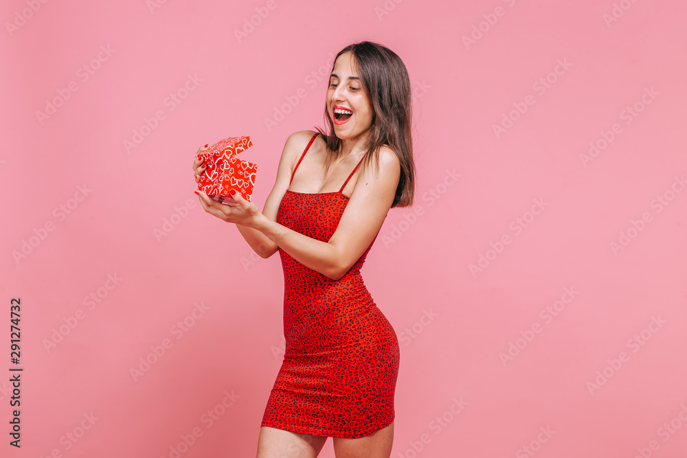 The girl received a box with a gift and rejoices on a pink background The girl received a box with a gift and rejoices on a pink background