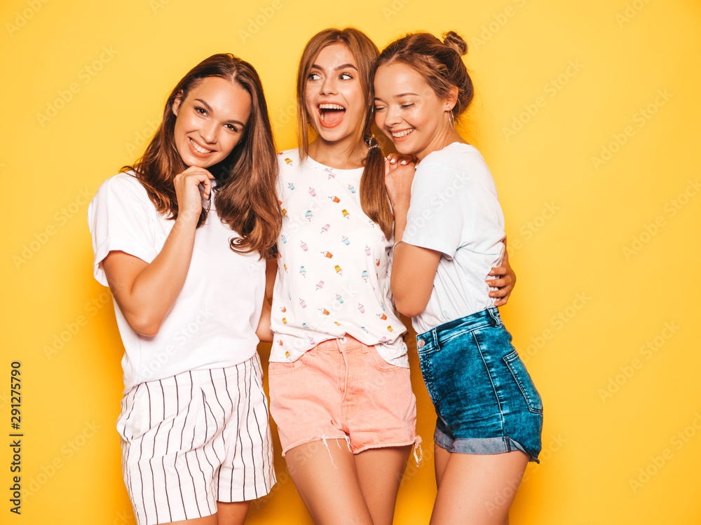 Three young beautiful smiling hipster girls in trendy summer clothes. Sexy carefree women posing near yellow wall in studio. Positive models going crazy and having fun Three young beautiful smiling hipster girls in trendy summer clothes. Sexy carefree women posing near yellow wall in studio. Positive models going crazy and having fun
