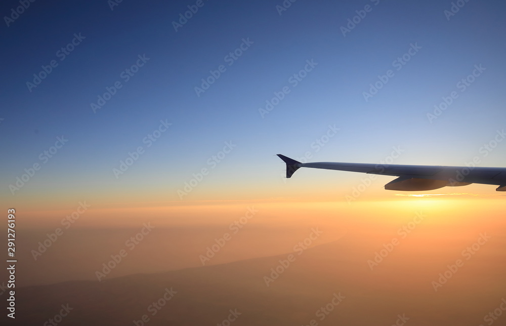 Sunset flight view with airplane wing silhouette