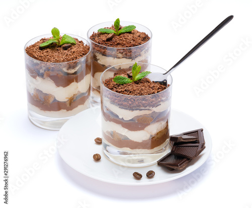 Classic tiramisu dessert in a glass cup on the plate and pieces of chocolate on white background with clipping path