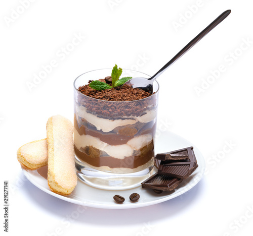 Classic tiramisu dessert in a glass cup on the plate and pieces of chocolate on white background with clipping path